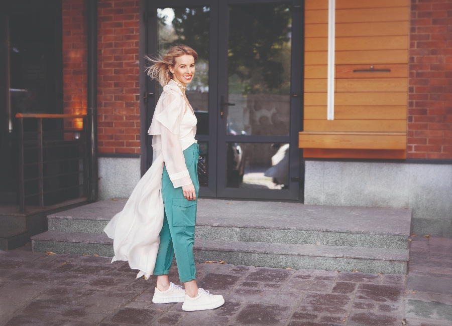 Beautiful Fashion Model smiling on City Street. Stylish Woman Wearing Fashionable Spring or Autumn Clothes (beige trench coat, oversize khaki cargo pants, accessorie) Outdoors. Trend outfit